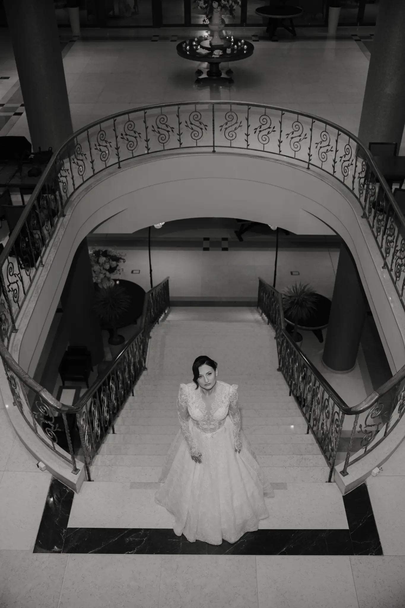 Bride beneath a dramatic staircase in black and white