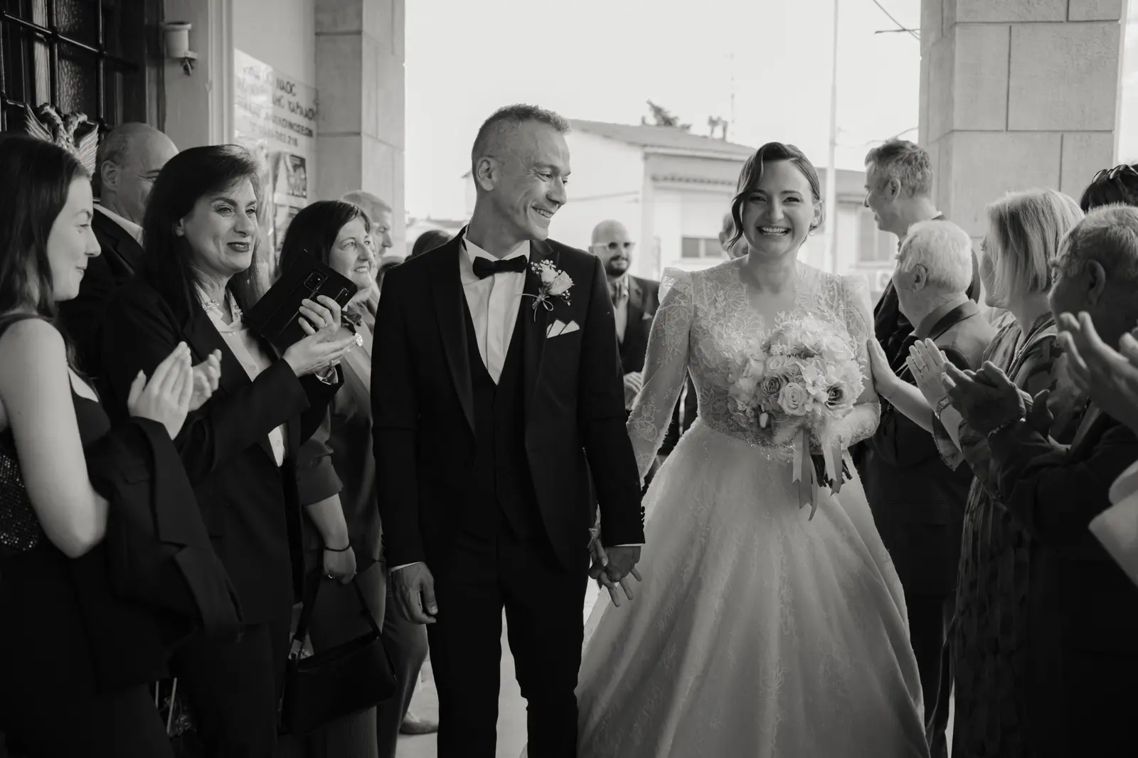 Newlyweds walking through a cheering crowd in black and white