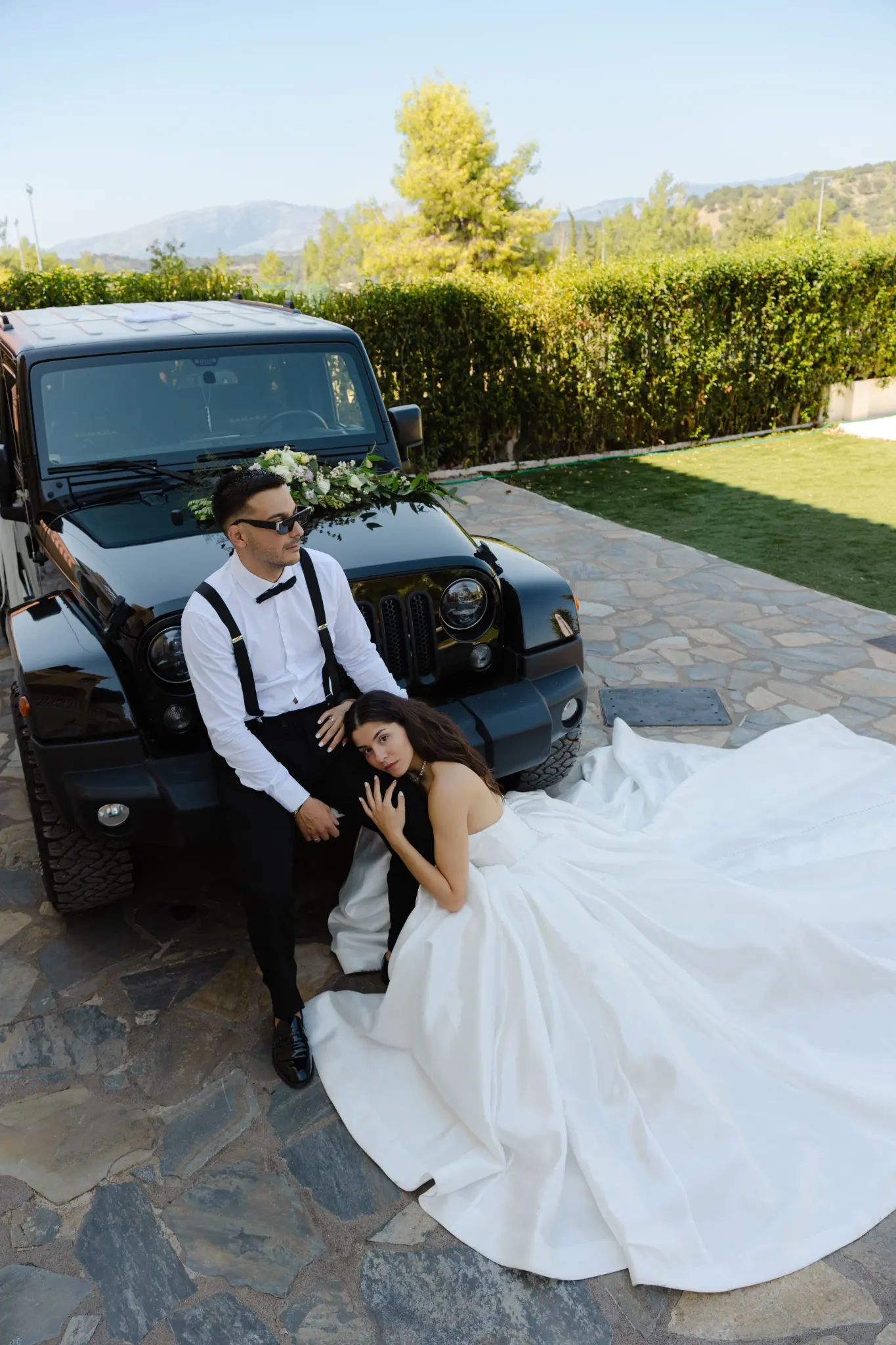 Bride and groom sitting together by a Jeep